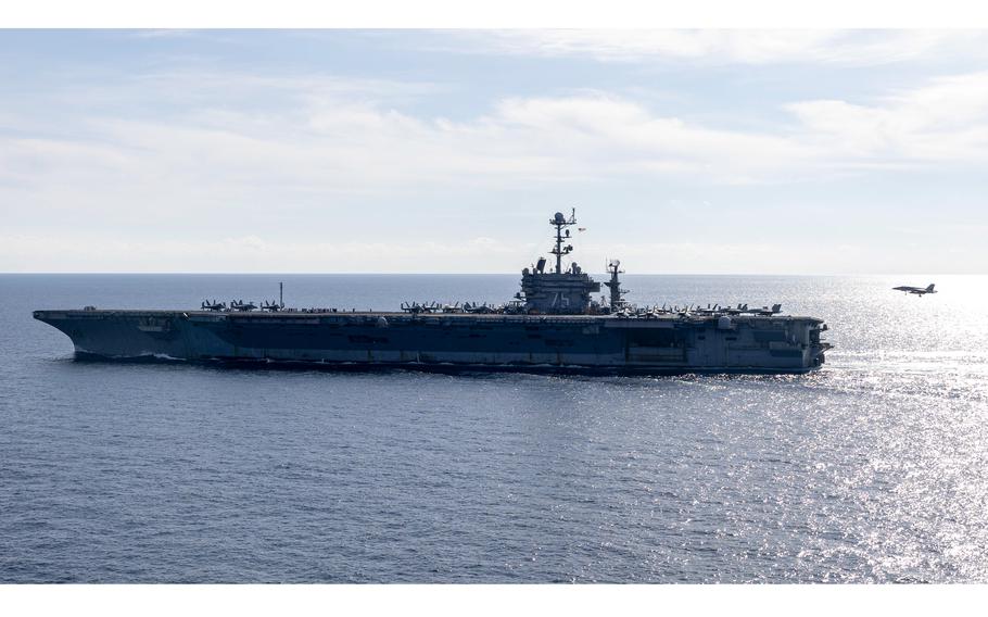 The USS Harry S. Truman underway at sea as a fighter jet prepares to land on deck.