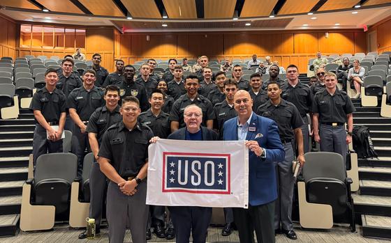 James Patterson (center) and 1st Sgt. Matt Eversmann (right) hold a USO flag