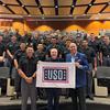 James Patterson (center) and 1st Sgt. Matt Eversmann (right) hold a USO flag