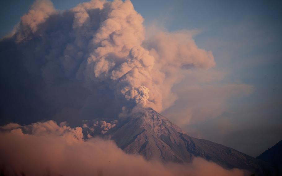 A volcano blows a thick cloud of ash