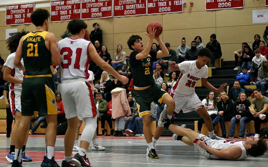 SHAPE's Aberto Saldana jumps for a shot over Raider Conner Kelly, bottom right, during a Jan. 12, 2024, game at Kaiserslautern High School in Kaiserslautern, Germany.