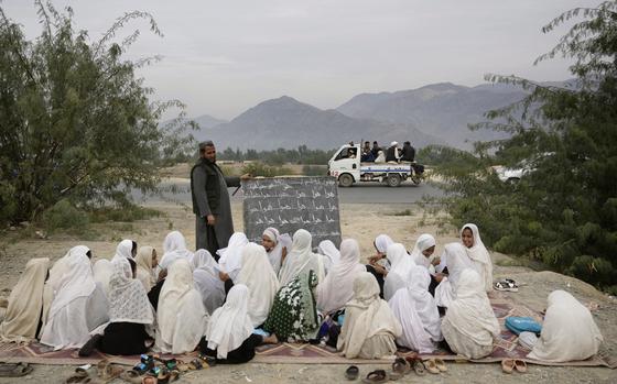 FILE -Afghan refugees pass by an outdoor girls classroom in Torkham, Afghanistan, Saturday, Nov. 18, 2023. (AP Photo/Ebrahim Noroozi, File)