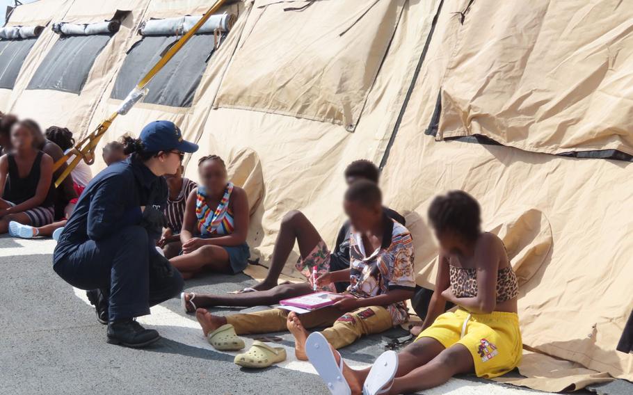 A crewmember from the U.S. Coast Guard Cutter Escanaba checking on multiple people from Haiti.