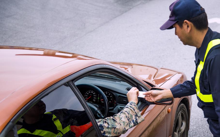 A Japanese gate guard checks a Marine’s indentification at Camp Foster, Okinawa, March 1, 2017.