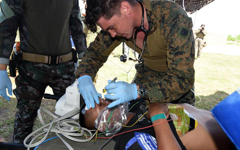 A man checks the eyes of another who is laying down.