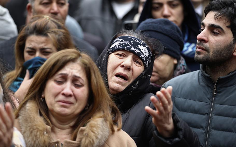 Mourners gather in a crowd.