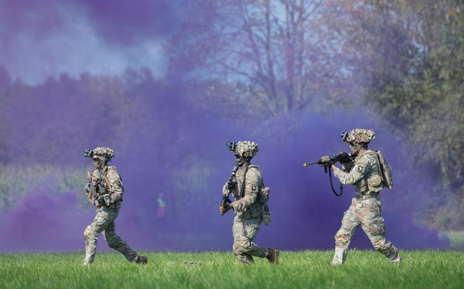 Soldiers with the 101st Airborne Division run through purple smoke during an air assault demonstration