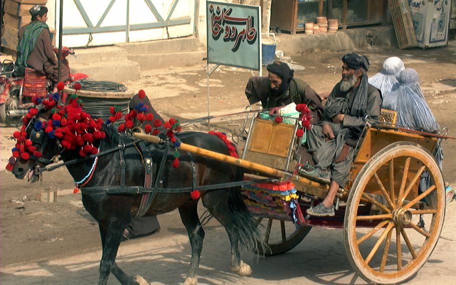 Afghan locals are transported by a horse carrier