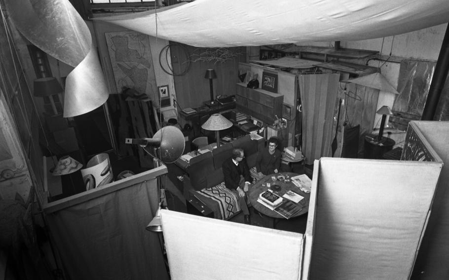 Artist Man Ray, and his wife Juliet Man Ray, née Browner, inside their home and the artist's studio in Paris. Several of the artist's works can be seen. Mrs. Ray, her husband's muse and companion, married the artist in 1946 after meeting him earlier that decade in Los Angeles.