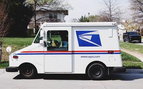 A United States Postal Service truck sits on a street outside a home.