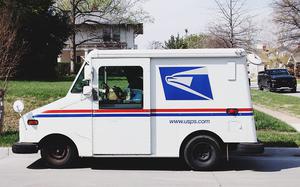 A United States Postal Service truck sits on a street outside a home.