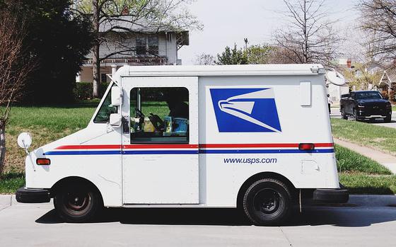 A United States Postal Service truck sits on a street outside a home.