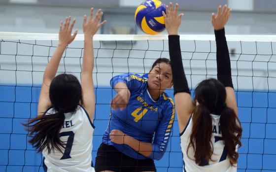 Yokota's Tai Anu hits between Osan American's Audrey Riel and Tiffany Pak during Saturday's inter-district volleyball match. The Cougars won in four sets.