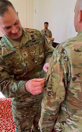 A general places a new patch on a soldier’s shoulder.