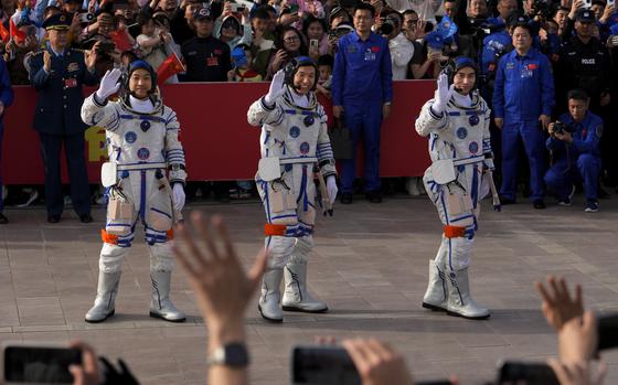 Chinese astronauts wave to a crowd.