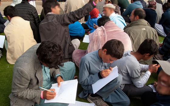 Afghan men and boys write during an English lesson at a military base in Germany.