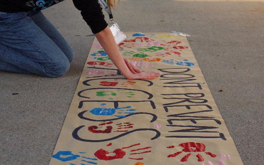 Students put their painted hand prints on protest signs.