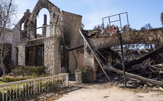 A basketball is stuck in the net outside of a residence destroyed by the Palisades Fire in the Pacific Palisades neighborhood of Los Angeles, Friday, Jan. 24, 2025. (AP Photo/Damian Dovarganes)