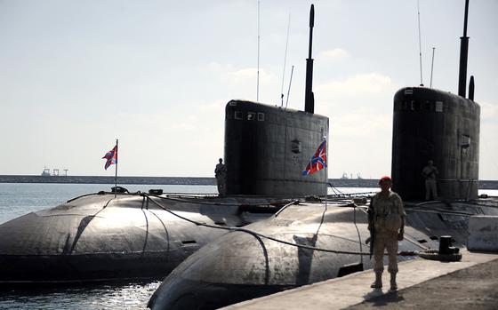 A Russian soldier stands next to submarines at the Russian naval base in the Syrian Mediterranean port of Tartus.