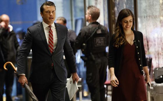 A man in a dark suit walks through the lobby of an office building.