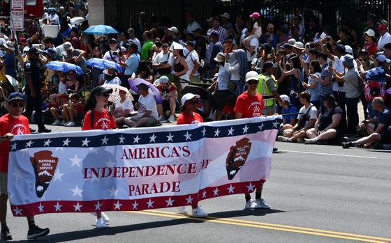 Parade volunteers carry a banner at the start of the parade that reads: “America’s Independence Day Parade.”