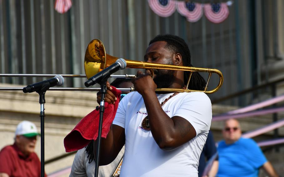 A member of The Experience Band and Show blows a trombone on the steps of the National Archives on July 4, 2024.