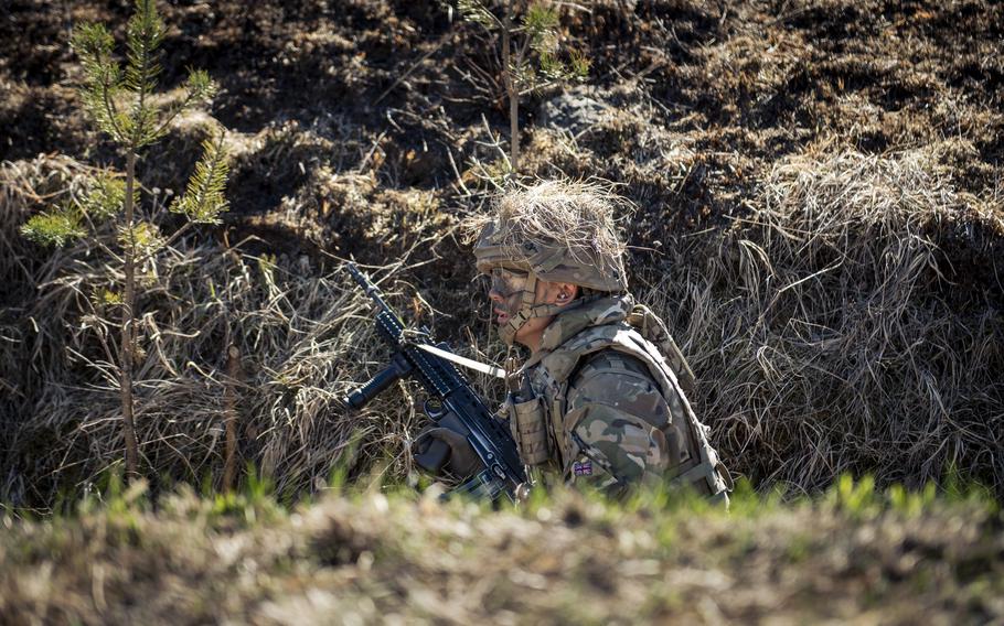 A cadet kneels in a trench