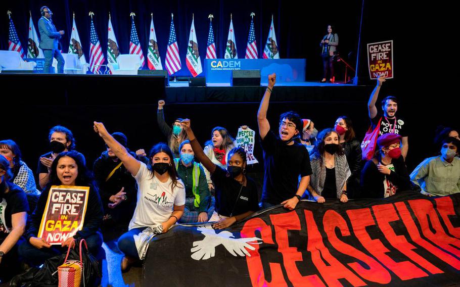 Demonstrators calling for a cease-fire in the Israel-Hamas war sit in front of the stage Nov. 18, 2023, disrupting the afternoon session at the Democratic nominating convention in the SAFE Credit Union Convention Center in Sacramento.