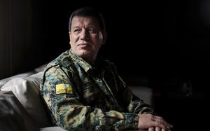 A man sits in military uniform for a portrait style photo.