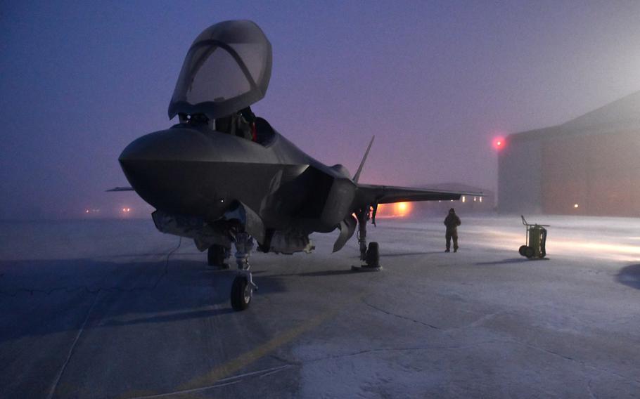 A F-35A Lightning II aircraft sits on a frosty runway with its canopy open. 