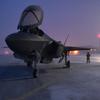 A F-35A Lightning II aircraft sits on a frosty runway with its canopy open. 