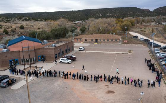 A line of people stands outside of a voting center 