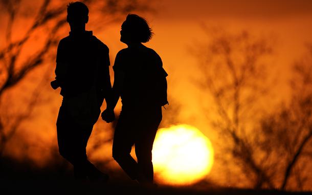 FILE - A couple walks through a park at sunset, March 10, 2021, in Kansas City, Mo. U.S. life expectancy rose in 2022 — by more than a year — after plunging two straight years at the beginning of the COVID-19 pandemic, according to a new government report released Wednesday, Nov. 29, 2023. The rise was mainly due to the waning of the pandemic in 2022, researchers said at the Centers for Disease Control and Prevention. (AP Photo/Charlie Riedel, File)