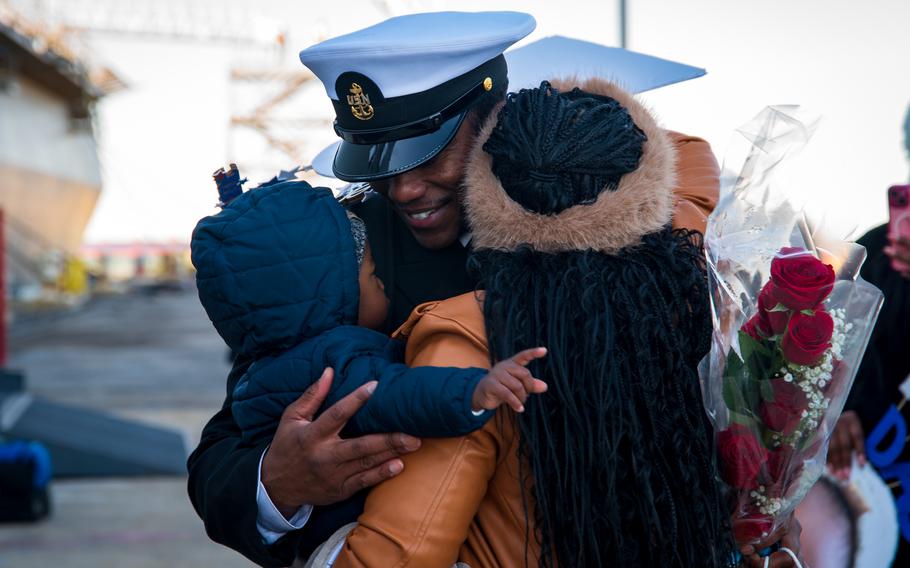 A sailor embraces his wife and child.