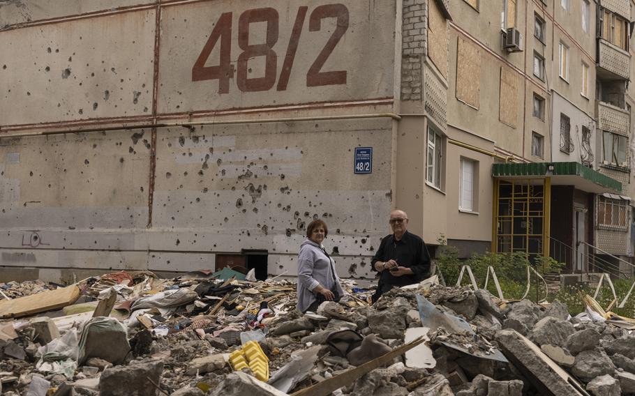 Tetiana and Leonid Zhuk stand outside their damaged apartment building in Kharkiv last month.