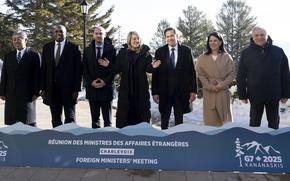 Seven foreign ministers representing the G7 member states stand for a family photo behind a short display for the summit.