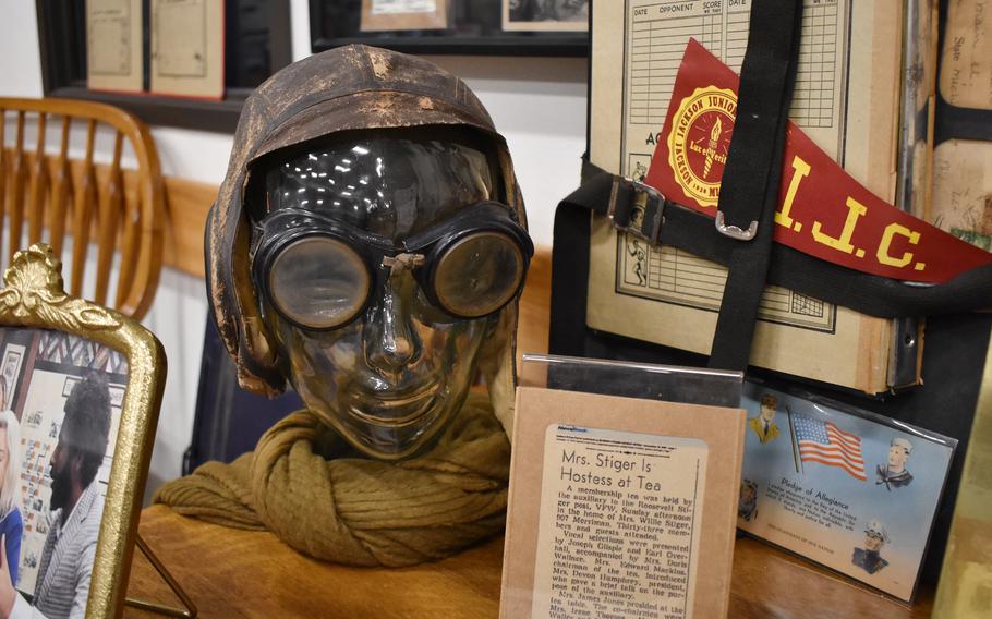 A pilot’s hat and googles are featured as a part of a collection.