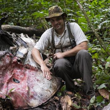 Justin Taylan, director of Pacific Wrecks, poses May 16, 2024, in Papua New Guinea at the crash site of a P-38 fighter once flown by flying ace Richard Bong.