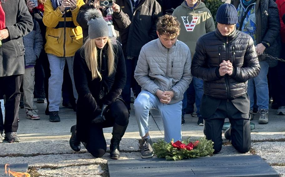 Anthony Shriver, right, says a prayer after laying a wreath at the grave of his uncle, President John F. Kennedy, during Wreaths Across America at Arlington National Cemetery, Dec. 14, 2024. With him are his partner, Catherine Anne Hennessey, and his son, Joseph.