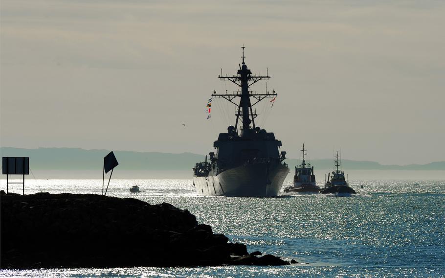 The ship sails towards land, surrounded on one side by two smaller ships.