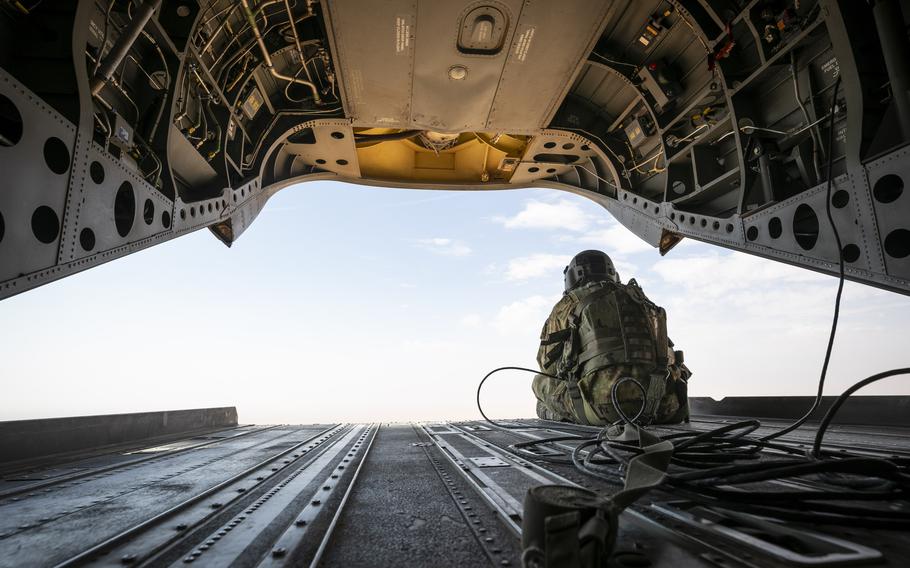 Soldier sitting and looking out the back of an Army helicopter.