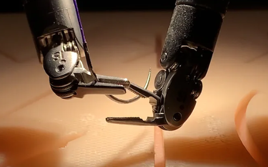 Robotic arms hold a thread.