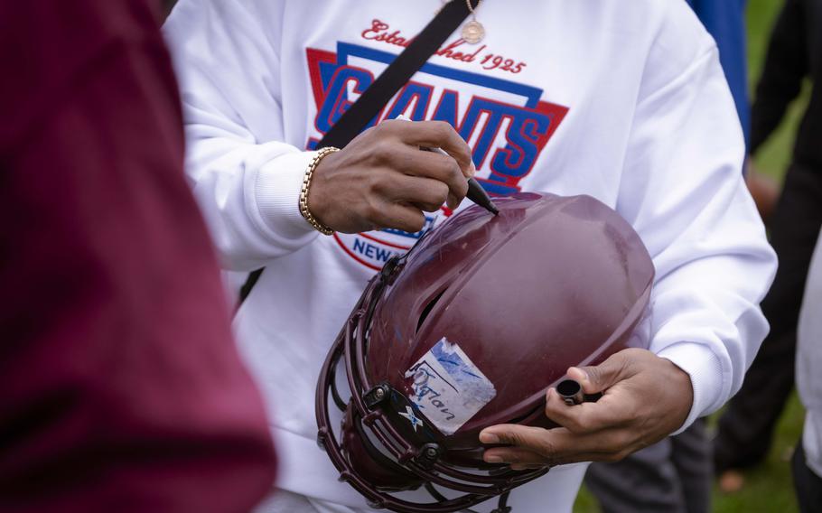 Former New York Giants player Victor Cruz signs a Vilseck High School student’s football helmet during a visit on Nov. 7, 2024. The team is set to play the Carolina Panthers on Sunday in Munich as part of the NFL’s International Series.