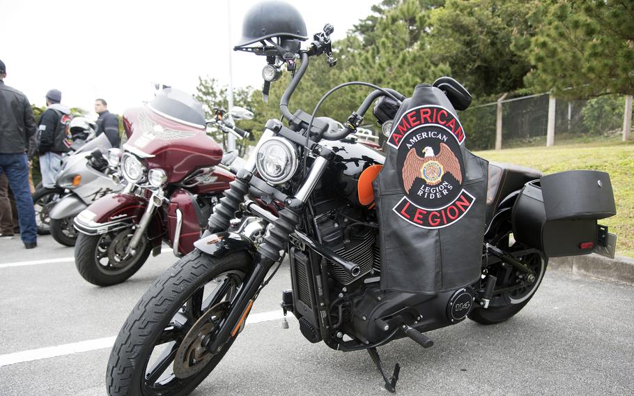 A motorcycle is parked with a jacket on it that says American Legion.