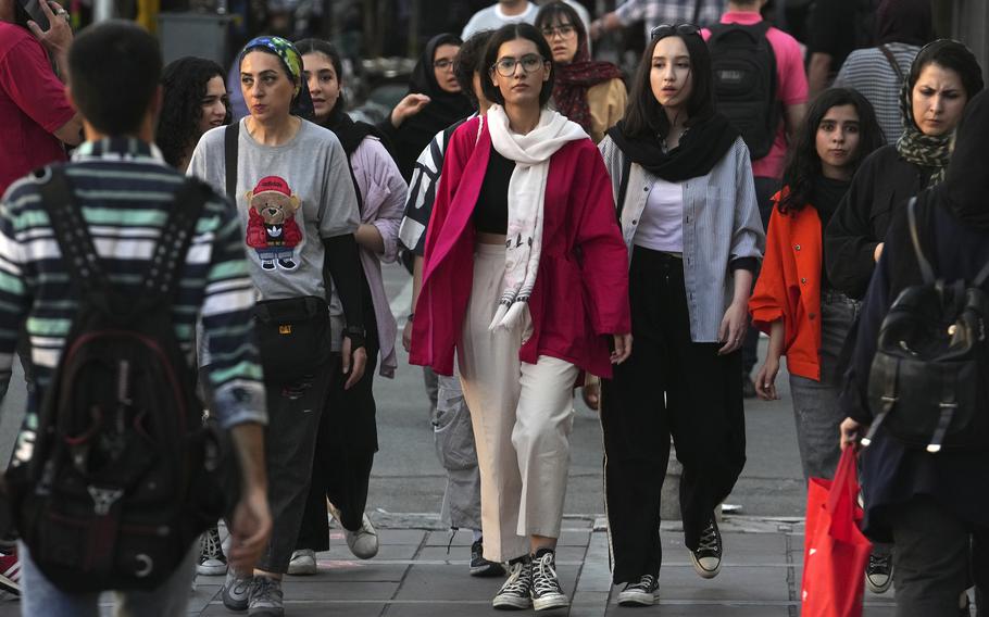 Iranians walk on a busy street in Tehran, four of five of them are women who are not wearing headscarves.