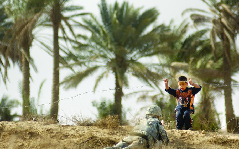 Sgt. Paul Levesque, a soldier from 1st Platoon, Company A, Task Force 3-66 Armor, gets a visit from a young Iraqi boy while pulling security Feb. 21, 2009 in Tahweela, Iraq. 