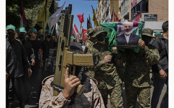 FILE - A boy holds a toy machine gun, as Hamas fighters, right, carry a mock coffin of Hamas political chief Ismail Haniyeh who was killed in an assassination in Tehran, during a symbolic funeral in Beirut, Lebanon, Friday, Aug. 2, 2024. (AP Photo/Hussein Malla, File)