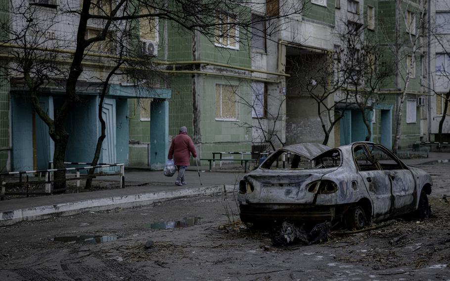 A woman walks past a burned-out car on Dec. 10, 2024.