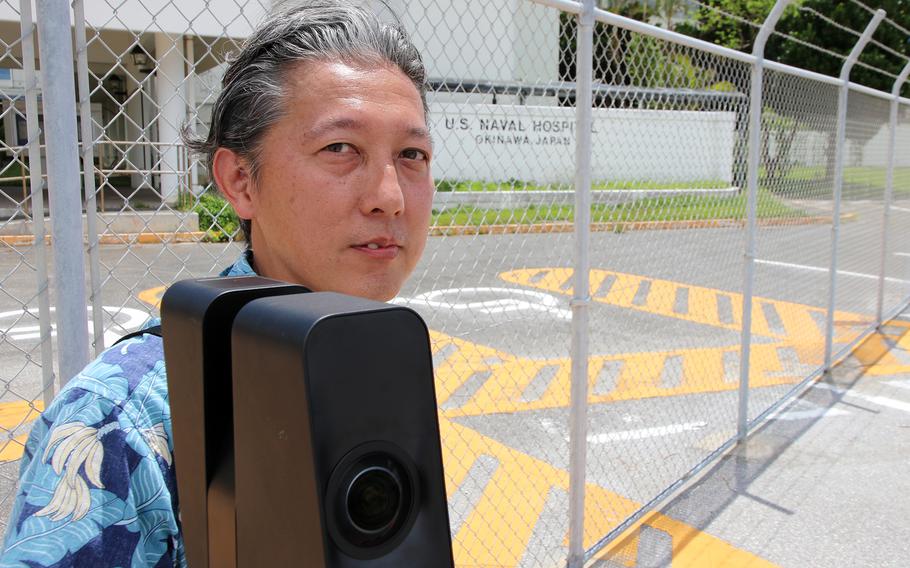 Taku Ikemiyagi, president of the Naha-based printing and 3D scanning firm Ikemiya Shokai Co. Ltd., poses with a 3D camera outside the old naval hospital on Camp Lester, Okinawa, Aug. 24, 2023.