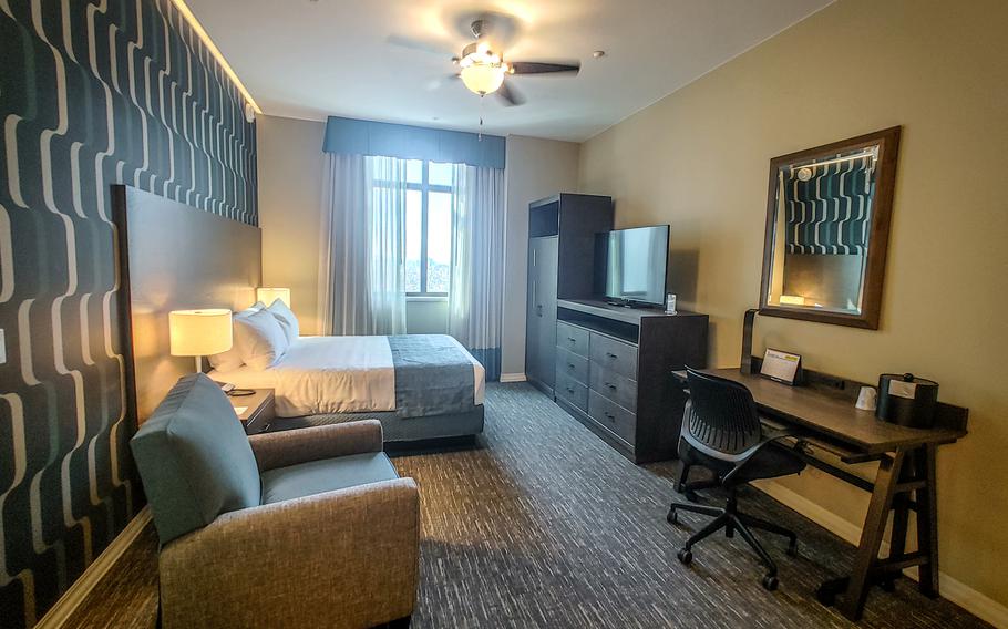 A bed, desk and living room-style chair decorate a room at the Camp Walker Lodge.